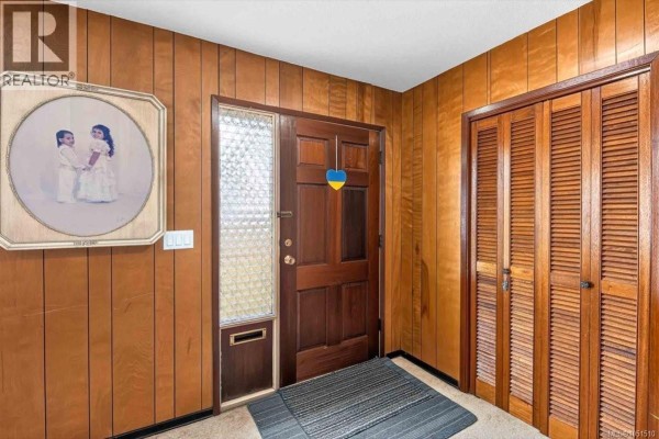 Dining area with a wooden table and chairs, adjacent to the kitchen. - 3962 Bruce St, Port Alberni