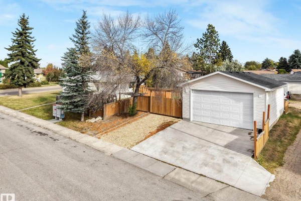 View of a detached garage with a white door and concrete driveway on a corner lot. - 3963 57 St Nw, Edmonton