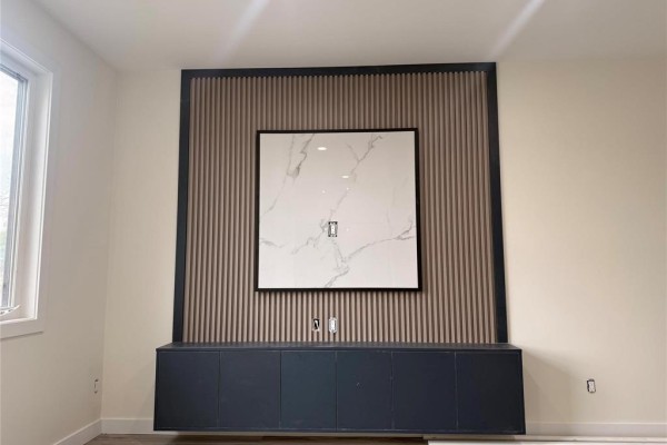 Close-up of a wall feature with vertical wood slats, a framed art piece, and dark cabinets. - 397 Kensington Street, Winnipeg