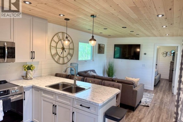 Wooden deck on covered porch with dining set and view of backyard amenities. - 398 68268 132a Range, Rural Lac La Biche County