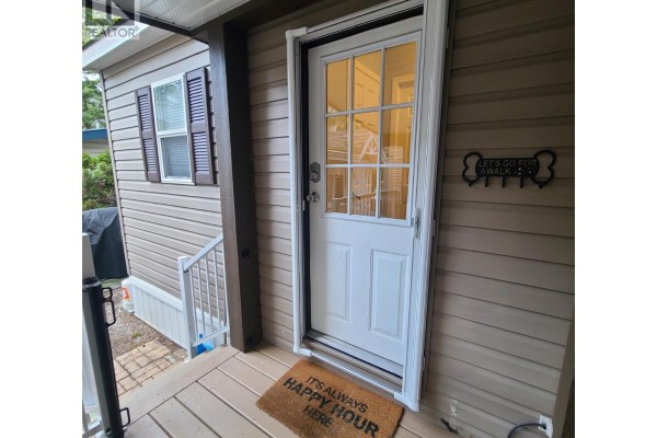 Close-up of the front door of a manufactured home with a welcome mat. - 3980 Squilax Anglemont Road Unit# 8, Scotch Creek