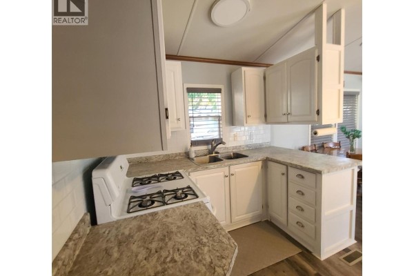 Corner kitchen with white cabinets, laminate countertops, and a gas stove. - 3980 Squilax Anglemont Road Unit# 8, Scotch Creek