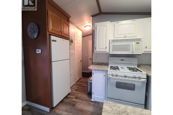 Kitchen with white appliances, wood cabinets, and gray wood-look flooring. - 3980 Squilax Anglemont Road Unit# 8, Scotch Creek