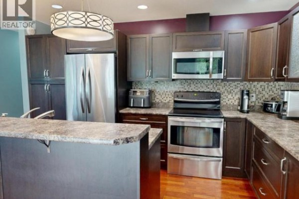 Kitchen with dark brown cabinets, granite countertops, stainless steel appliances, and wood floor. - 3980 Westview Ave, Powell River