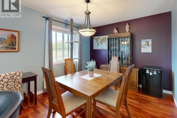 Backyard deck with patio furniture, cat enclosure, wooden fence, and green lawn. - 3980 Westview Ave, Powell River
