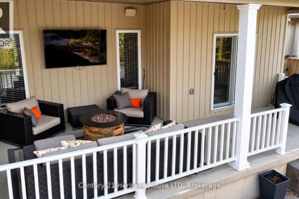 View of a covered back patio with white railings and steps leading to a concrete walkway. - 3984 Village Creek Drive, Fort Erie
