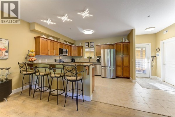 Kitchen with wood cabinets, granite countertops, stainless steel appliances, and island seating. - 3996 Beach Avenue Unit# 236, Peachland