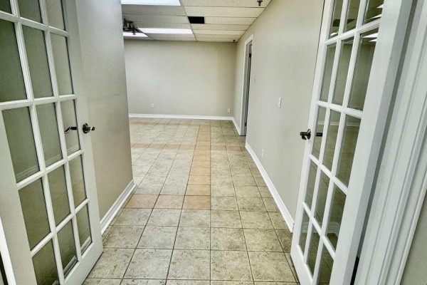 Building entrance with double glass doors, brick facade, and surrounding shrubs. - 3a - 400 Creditstone Road W, Vaughan