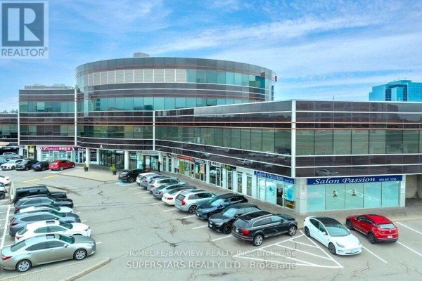 Aerial view of a commercial building with retail storefronts and a parking lot filled with cars under a cloudy sky. - 3a - 505 Highway 7 Highway E, Markham