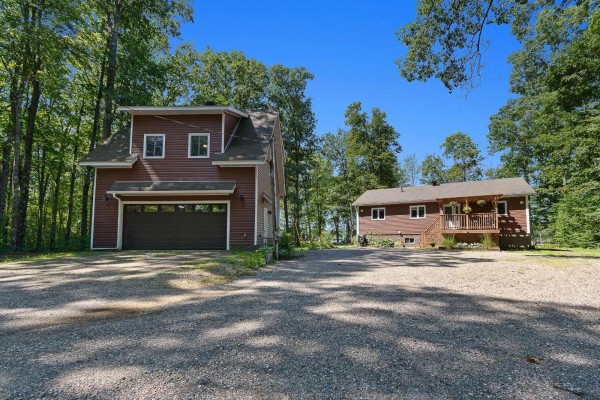 Two-story detached garage and a single-story house on a gravel driveway, surrounded by woods. - 3a Ch. Pearson, Mansfield Et Pontefract