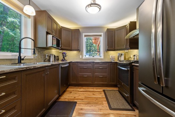 Dark wood kitchen with granite countertops, stainless steel appliances, and a window overlooking trees. - 3a Ch. Pearson, Mansfield Et Pontefract