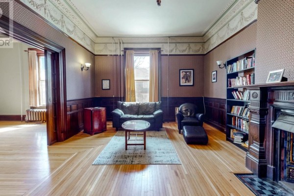 Living room with brown wallpaper, hardwood floors, a fireplace, and a leather sofa with a coffee table. - 3a Forest Road, St  John S