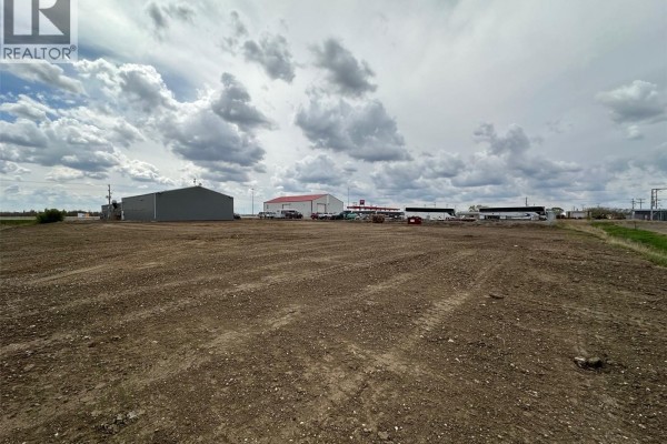 Open dirt area with distant commercial buildings and cloudy sky - 3c 820 N Service Road W, Moose Jaw