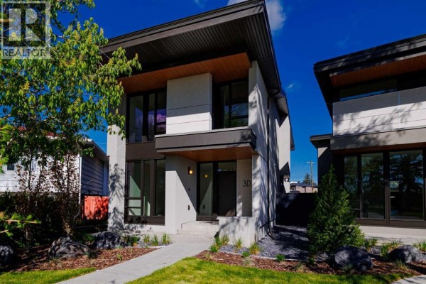 Modern two-story house exterior with light grey concrete, dark wood accents, and large windows under a blue sky. - 3d Willow Crescent Sw, Calgary