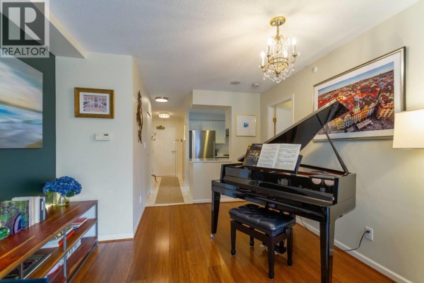 Entrance hall and living area featuring a grand piano, hardwood floors, and artwork. - 3f 199 Drake Street, Vancouver