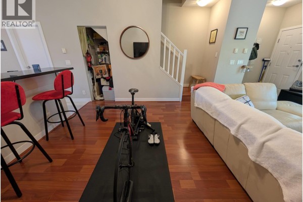 Kitchen island with red stools, stationary bicycle on mat, and view of staircase and living room. - 3xxx E 54 Avenue, Vancouver