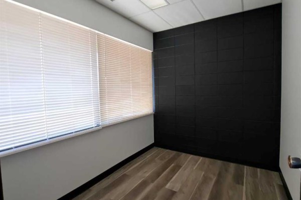 Small office room with wood-look flooring, white blinds on window, and a black accent wall. - 4, 6310 50th Avenue, Lloydminster