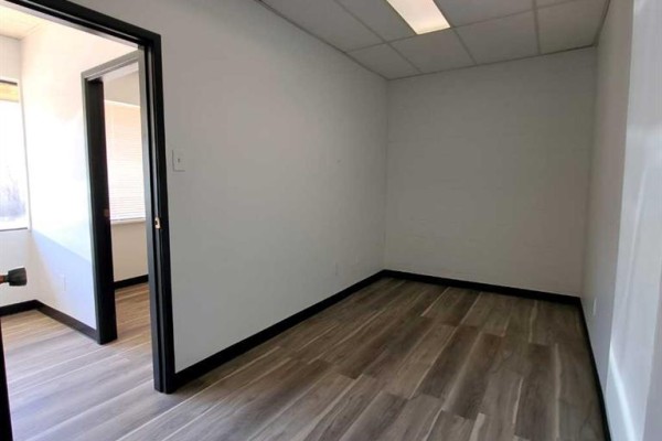 Interior of an empty office room with white walls, wood-look flooring, and a doorway to another room. - 4, 6310 50th Avenue, Lloydminster