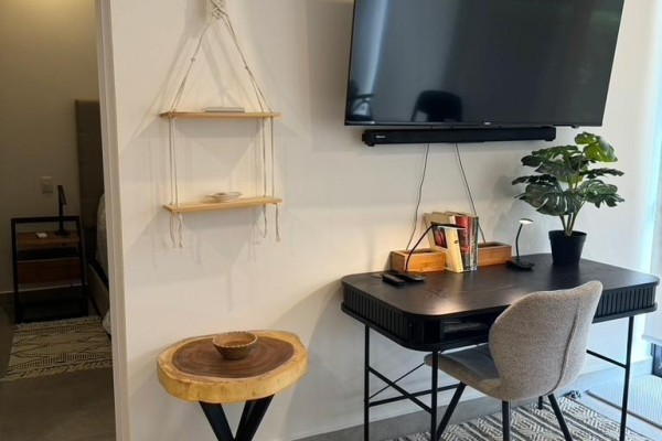 Corner of a room with a desk, chair, wall-mounted TV, and a small wooden side table. - #4 - 1 Azul Court, Costa Rica