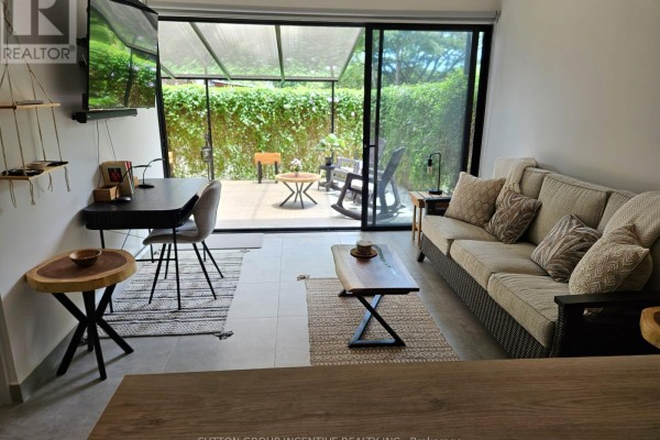 Living area with a sofa, coffee table, desk, and a sliding glass door opening to an outdoor patio. - #4 - 1 Azul Court, Costa Rica