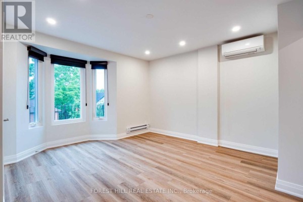 Kitchen featuring stacked washer and dryer, leading to a living area with window. - 4 - 1 Greensides Avenue, Toronto