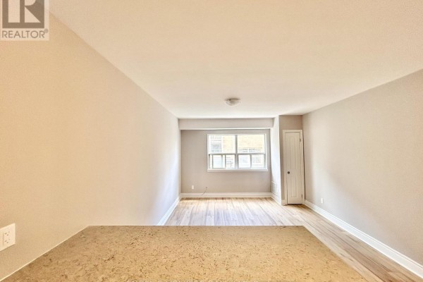View of living space with light wood floors and a large window. - 4 - 100 Twenty Fifth Street, Toronto