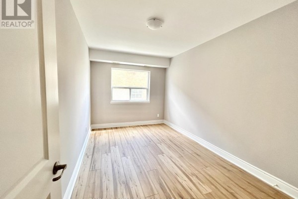 Bedroom with light wood floors and a window. - 4 - 100 Twenty Fifth Street, Toronto