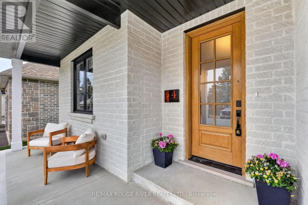Close-up of the front porch with wooden chairs, a wooden door, and potted flowers. - 4 - 1000 D'arcy Street, Cobourg