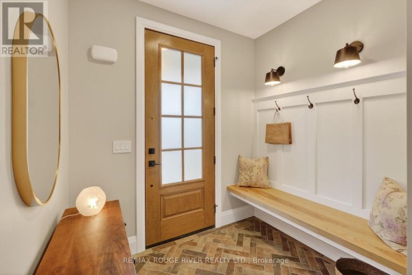Interior entryway with a wooden bench, coat hooks, a large mirror, and a wooden door. - 4 - 1000 D'arcy Street, Cobourg