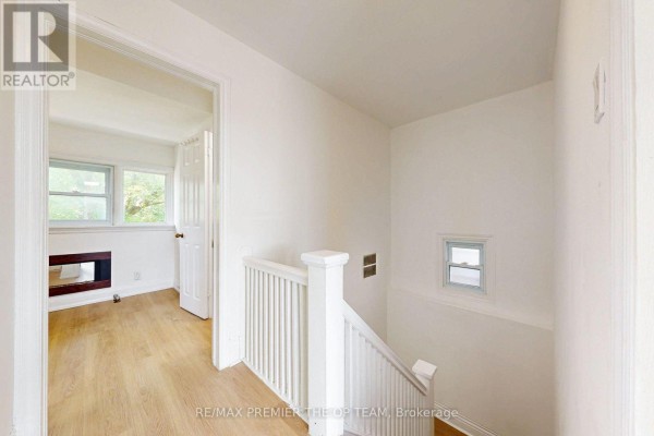 Hallway with a staircase, white banister, and a doorway leading to a bright room. - 4 - 11 Columbine Avenue, Toronto