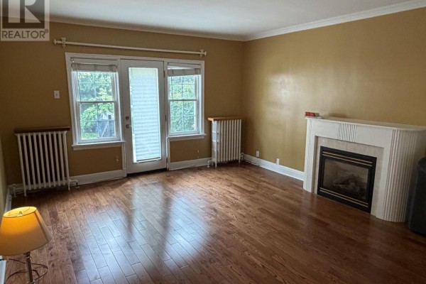 Living room with hardwood floors, fireplace, and glass doors leading outside. - 4 - 1217 Avenue Road, Toronto
