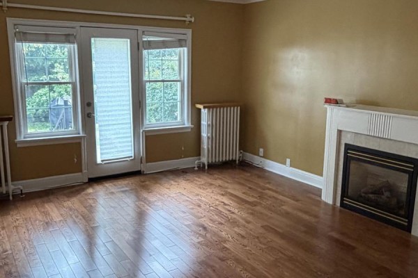 Living room with hardwood floors, fireplace, and glass doors leading outside. - 4 - 1217 Avenue Road, Toronto