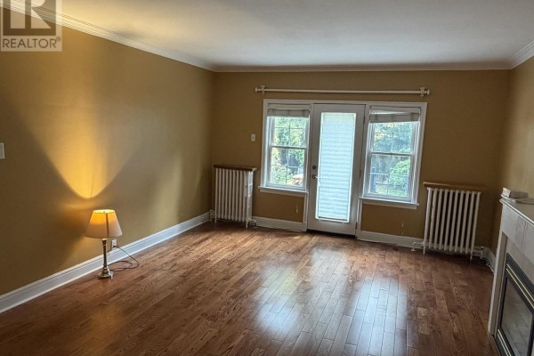 Living room with hardwood floors, fireplace, and glass doors leading outside. - 4 - 1217 Avenue Road, Toronto