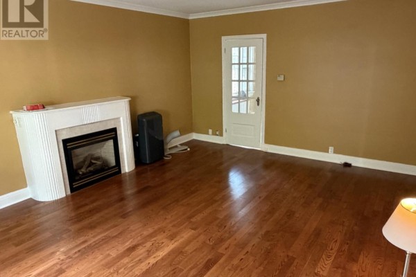 Living room with hardwood floors, fireplace, and a white paneled door. - 4 - 1217 Avenue Road, Toronto