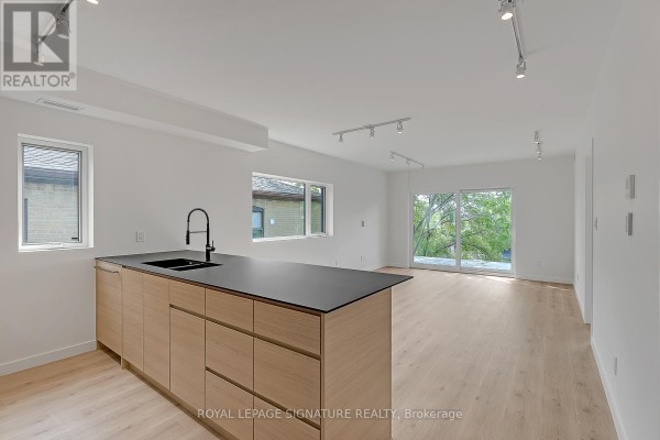 Open concept living space with a large kitchen island, dining area, and balcony access. - 4 - 1254 Davenport Road, Toronto