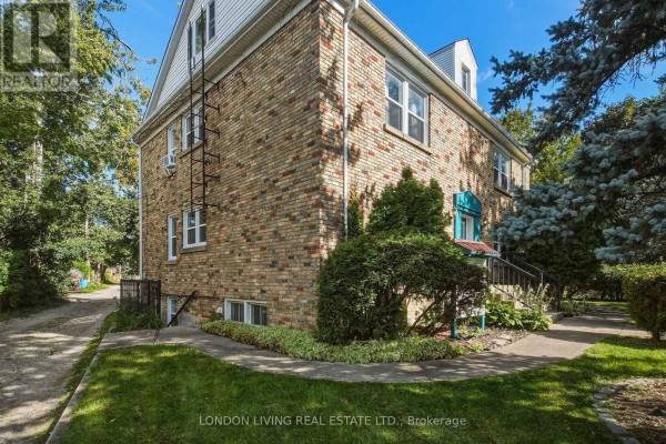 Side view of a brick building with trees, grass, and a driveway. - 4 - 137 Windsor Crescent, London South