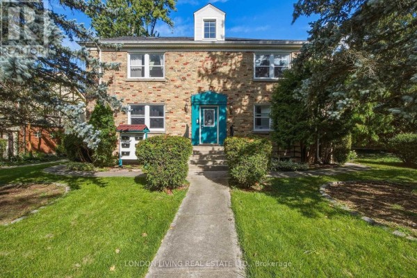 Front exterior of a brick building with a concrete walkway, green lawn, and trees. - 4 - 137 Windsor Crescent, London South