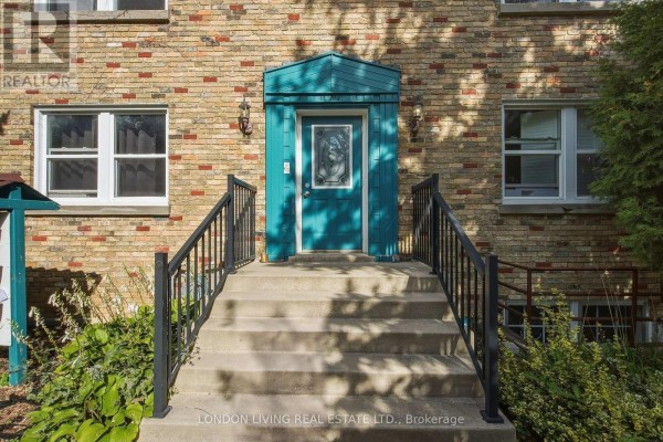 Front entrance of a brick building with concrete steps, black railings, and a teal door. - 4 - 137 Windsor Crescent, London South
