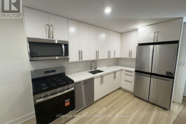 Modern kitchen with white cabinets, stainless steel appliances, and light wood-look flooring. - 4 - 150 Brunswick Avenue, Toronto
