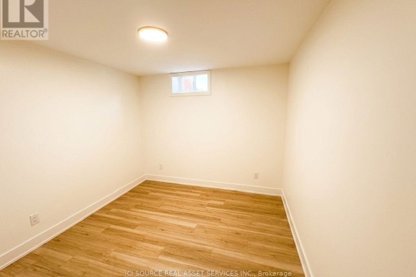 Empty room with light cream walls, wood-look flooring, and a small window. - 4 - 150 Brunswick Avenue, Toronto