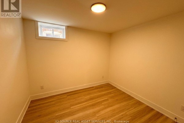 Empty room with light cream walls, wood-look flooring, and a small window. - 4 - 150 Brunswick Avenue, Toronto