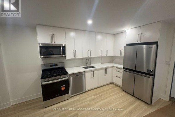L-shaped kitchen with white cabinets, stainless steel appliances, and light wood flooring. - 4 - 152 Brunswick Avenue, Toronto