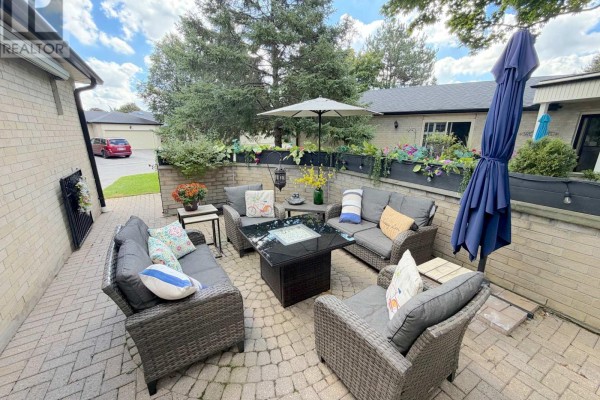 An outdoor patio area with seating, fire pit, and surrounding greenery. - 4 - 163 Pine Valley Drive, London South