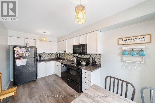 Kitchen with white cabinets, black appliances, mosaic tile backsplash, and a dining table. - 4 - 17 Cheltenham Road, Barrie