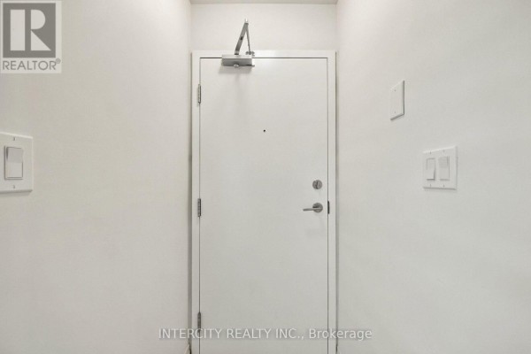 Interior view of a hallway with a closed white door and light-colored walls. - 4 - 235 Mclevin Avenue, Toronto