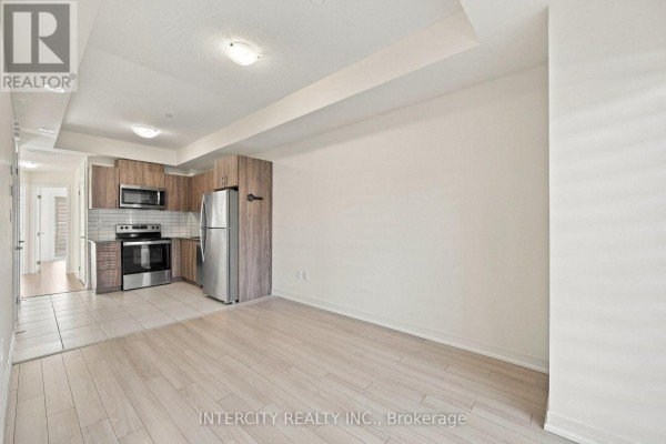 Open-concept living area and kitchen with light wood floors and stainless steel appliances. - 4 - 235 Mclevin Avenue, Toronto