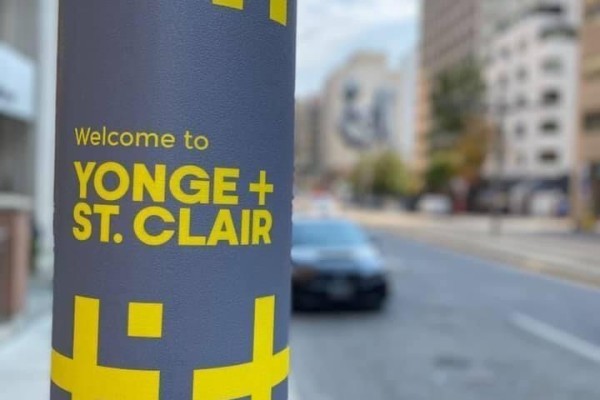 Sign reading "Welcome to Yonge + St. Clair" on a pole in a city setting. - 4 - 27 Glen Elm Avenue, Toronto