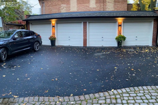 Triple garage with white doors, brick accents, and exterior lighting flanking the doors. - 4 - 27 Glen Elm Avenue, Toronto