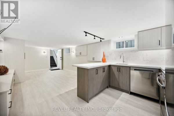 Bright basement kitchen with white countertops, grey cabinets, stainless steel appliances, and island. - 4 - 27 Glen Elm Avenue, Toronto