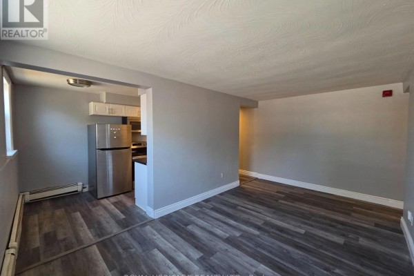 Living room with grey walls connecting to a kitchen with a stainless steel refrigerator. - 4 - 300 Montrave Avenue, Oshawa